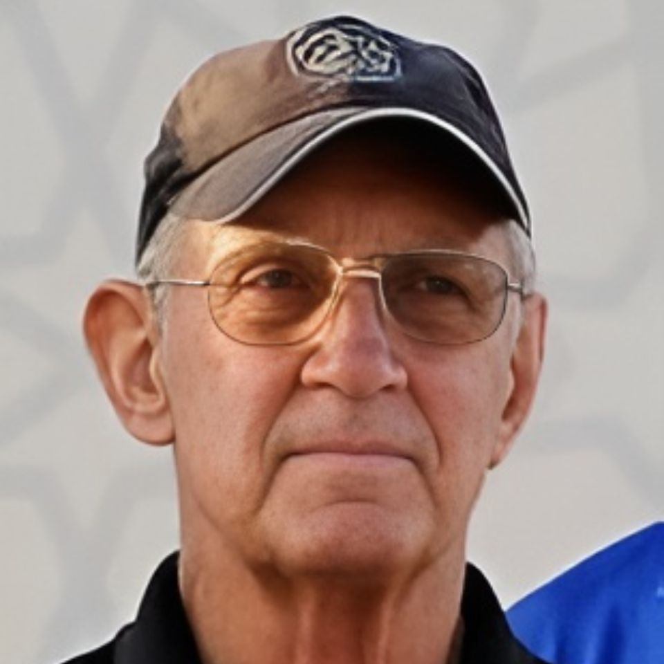 A man wearing a black baseball cap and glasses is looking ahead. The background is a light gray, blurred pattern.