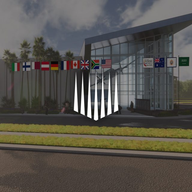 Modern building with palm trees and multiple international flags above the entrance, including Italy, Australia, Germany, and others. The design features triangular white elements in the foreground, casting shadows on the pavement.