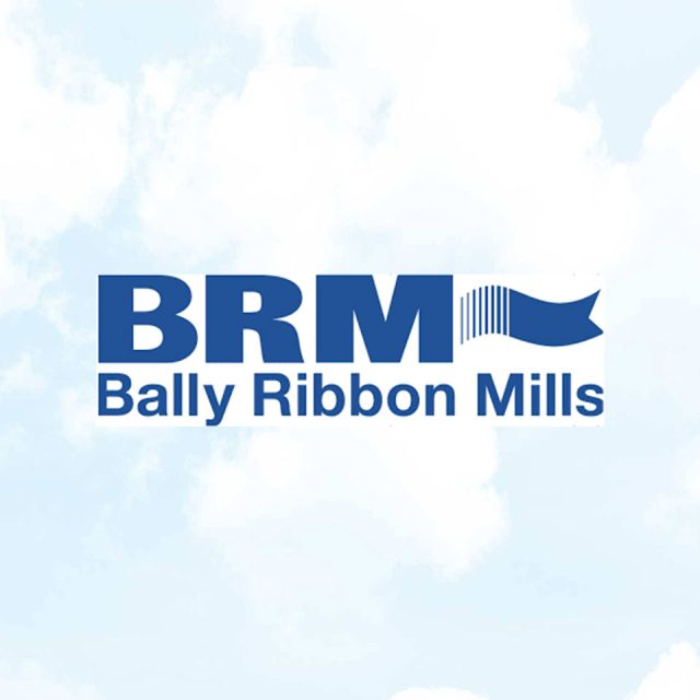 Logo of Bally Ribbon Mills with the acronym "BRM" in bold blue letters next to a stylized ribbon. The full name is written below in the same blue color. The background is a cloudy sky.